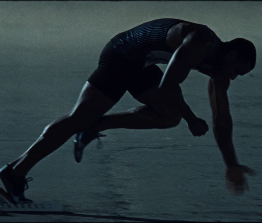 A sprinter driving out of the blocks on an empty track at dusk