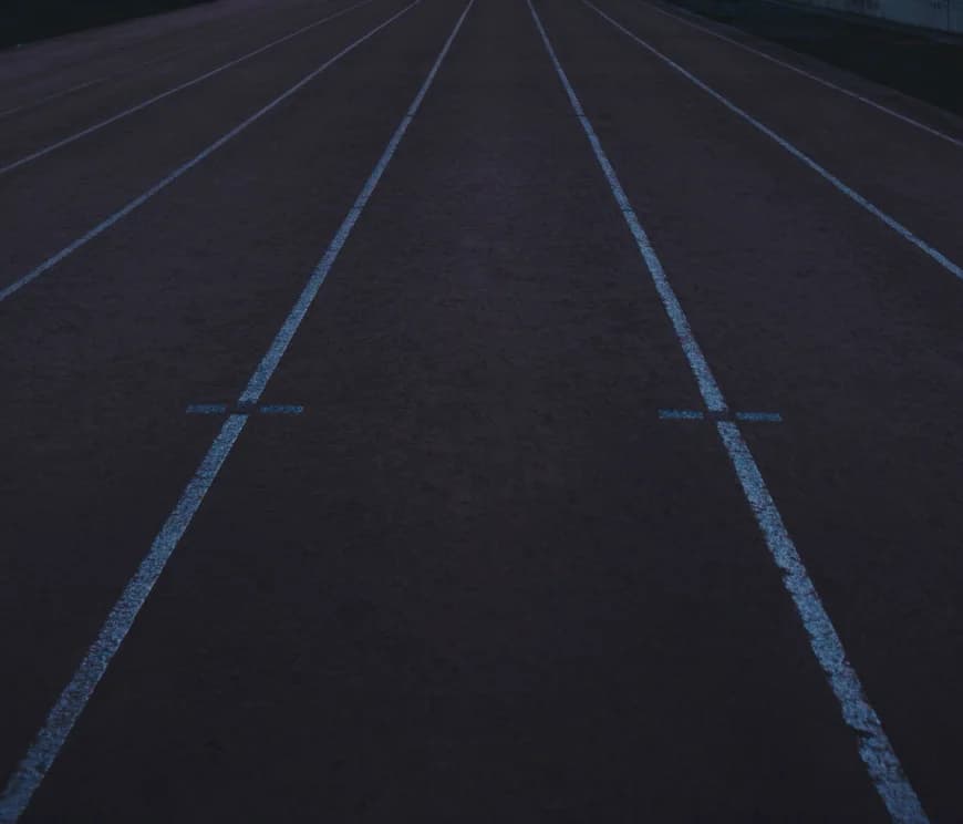 Empty painted lane lines running away down a weathered outdoor track